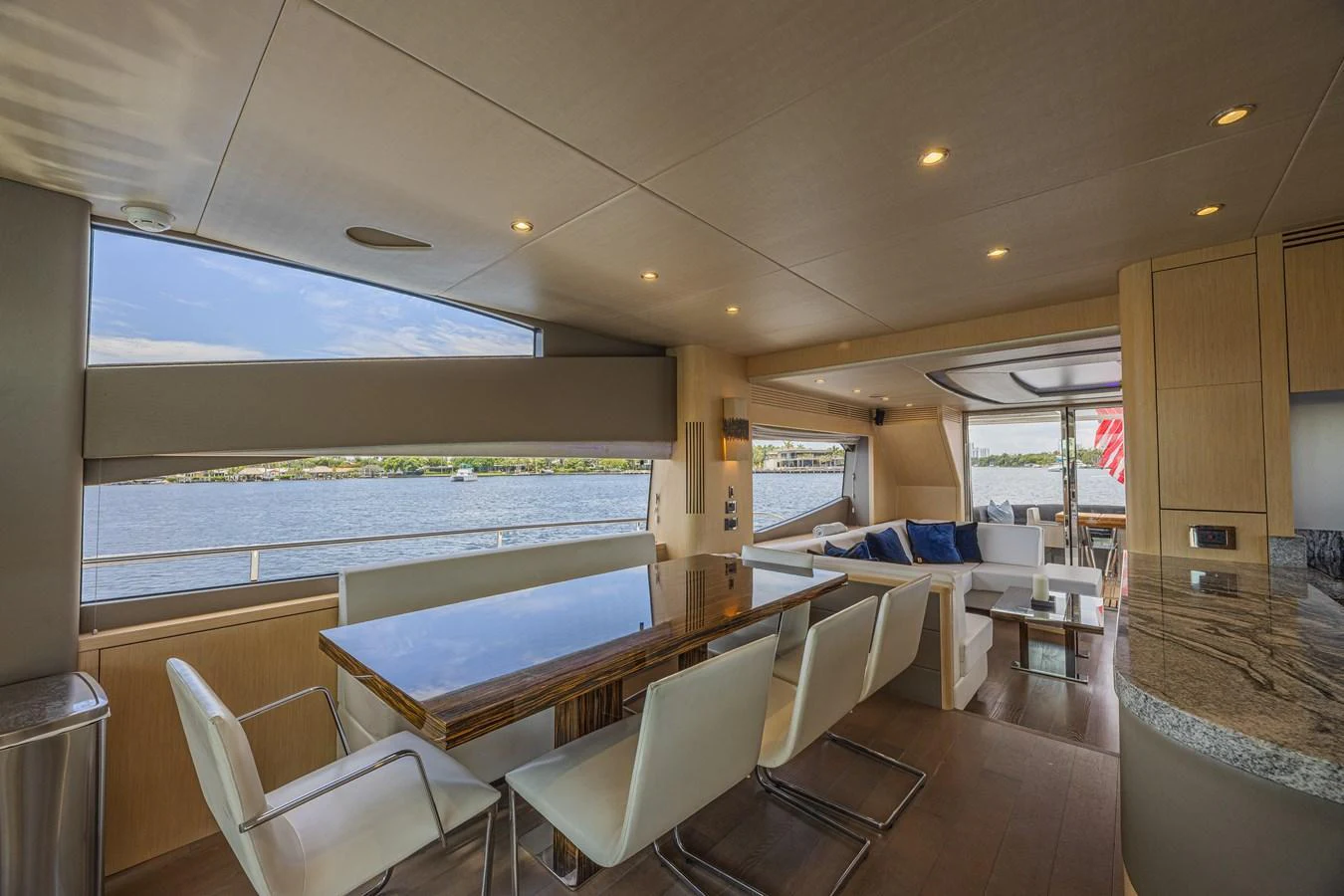 The yacht's salon features a spacious dining area with a large table and modern chairs, complemented by panoramic windows offering stunning water views. aboard DIRTY DAWG Yacht for Sale