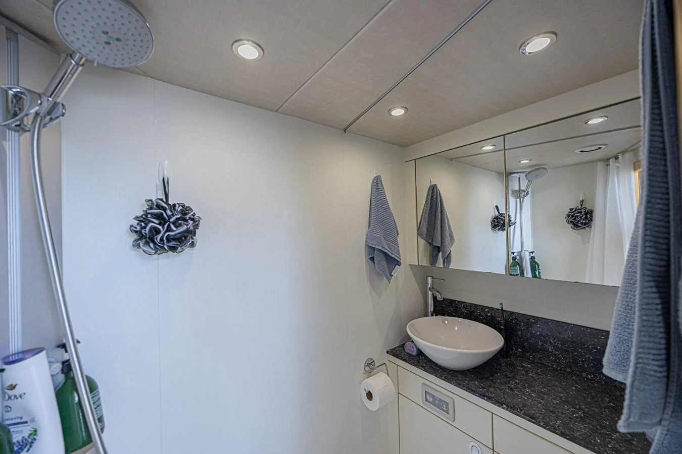 The yacht's bathroom features a modern sink, a large mirror, and a sleek shower area. aboard DIRTY DAWG Yacht for Sale
