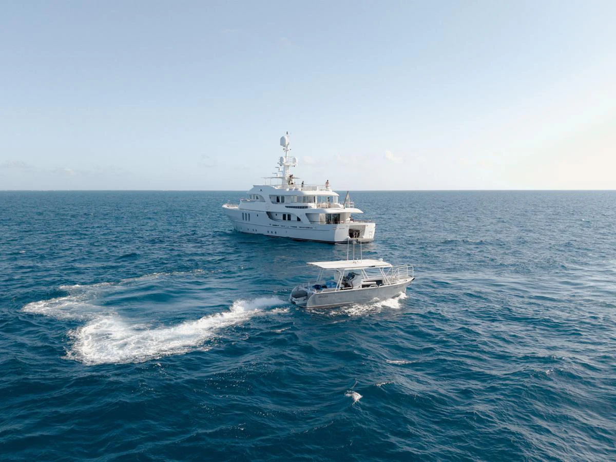 A luxurious yacht cruises on the open sea, accompanied by a smaller tender boat. aboard BELUGA Yacht for Sale