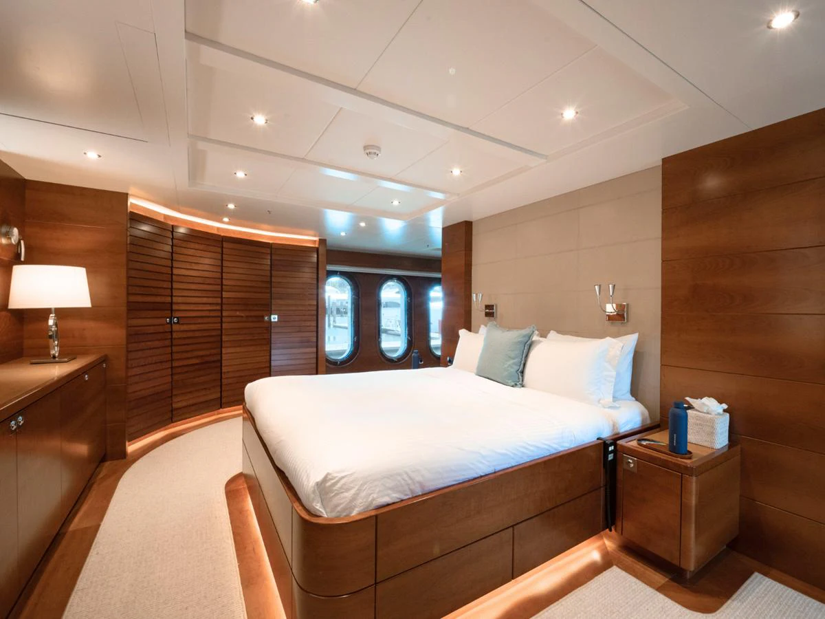 The master stateroom features a luxurious bed with elegant wood paneling and ambient lighting. aboard BELUGA Yacht for Sale