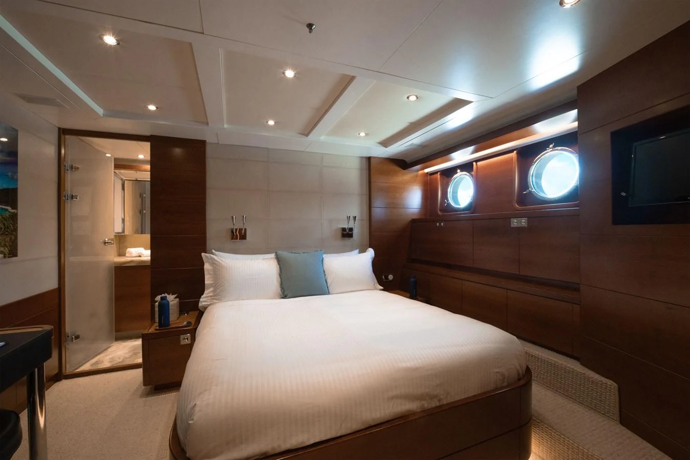 A luxurious stateroom featuring a comfortable bed, warm lighting, and elegant wood paneling. aboard BELUGA Yacht for Sale