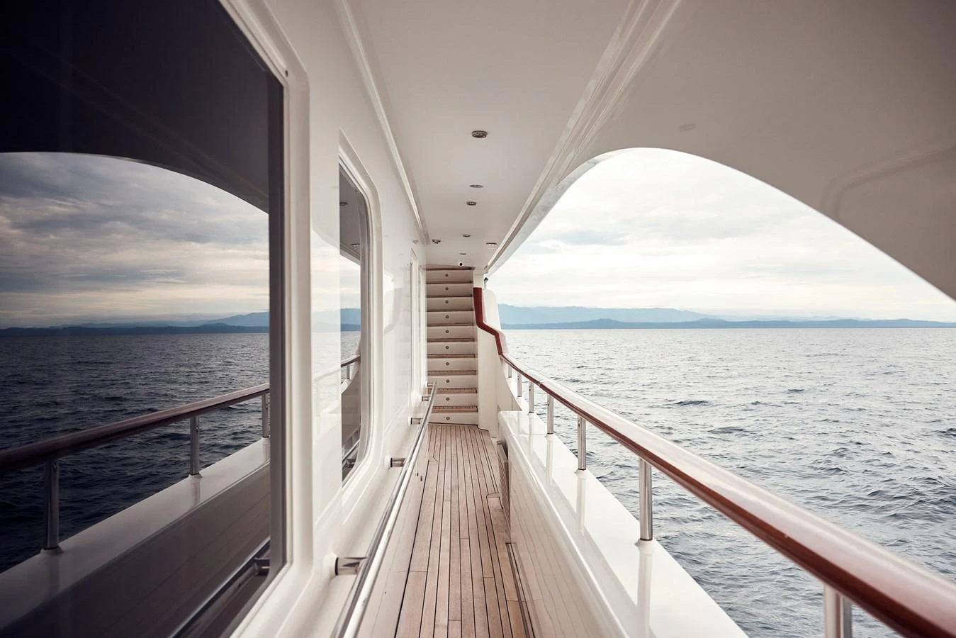 A serene view of the yacht's side deck with polished wooden railings and expansive ocean scenery. aboard BELUGA Yacht for Sale