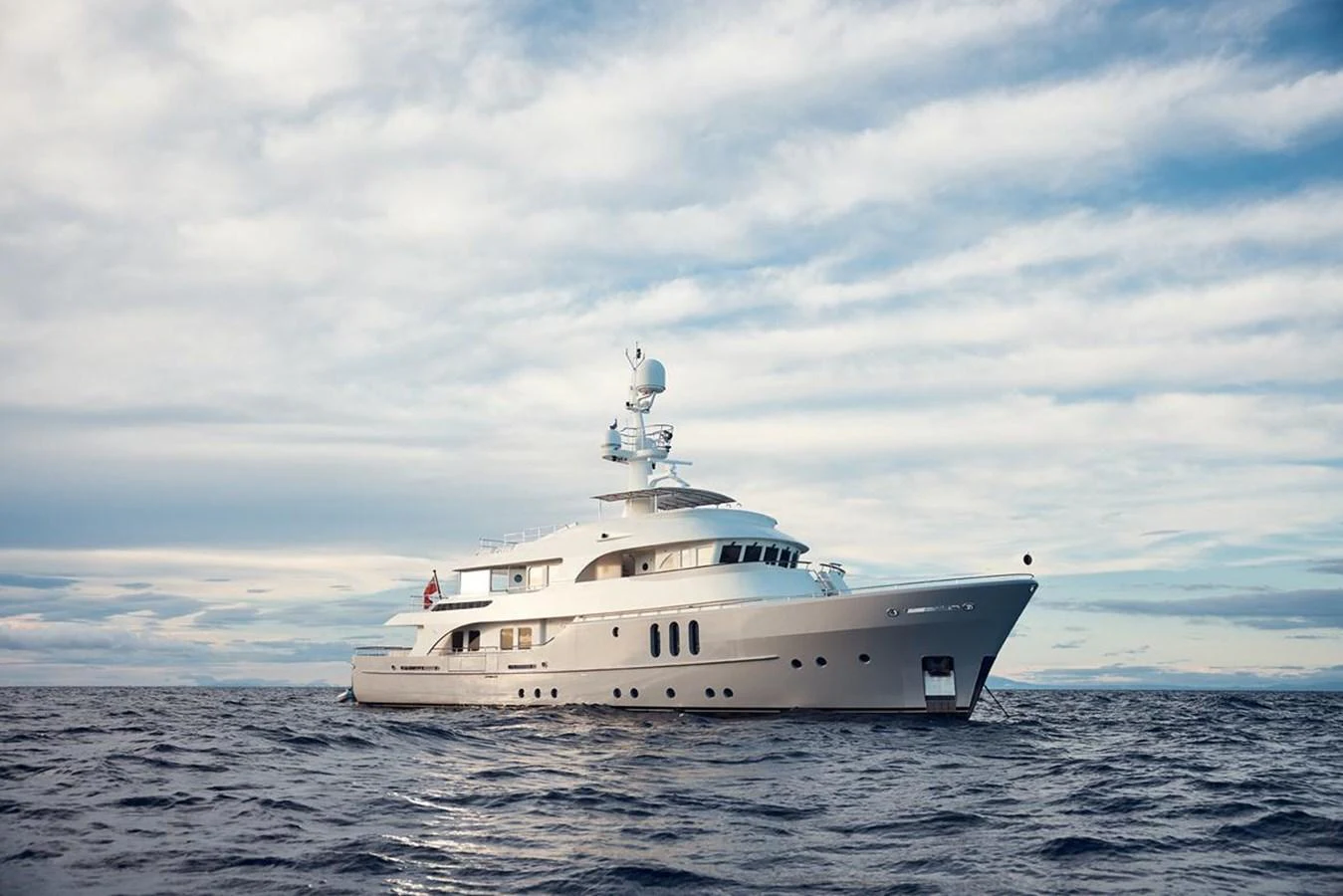 A sleek and elegant yacht cruising on the open sea under a partly cloudy sky. aboard BELUGA Yacht for Sale