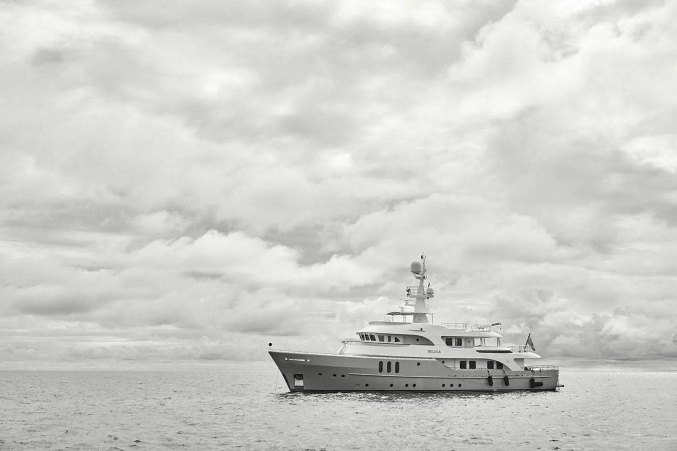 A majestic yacht sails gracefully on calm waters under a cloudy sky. aboard BELUGA Yacht for Sale