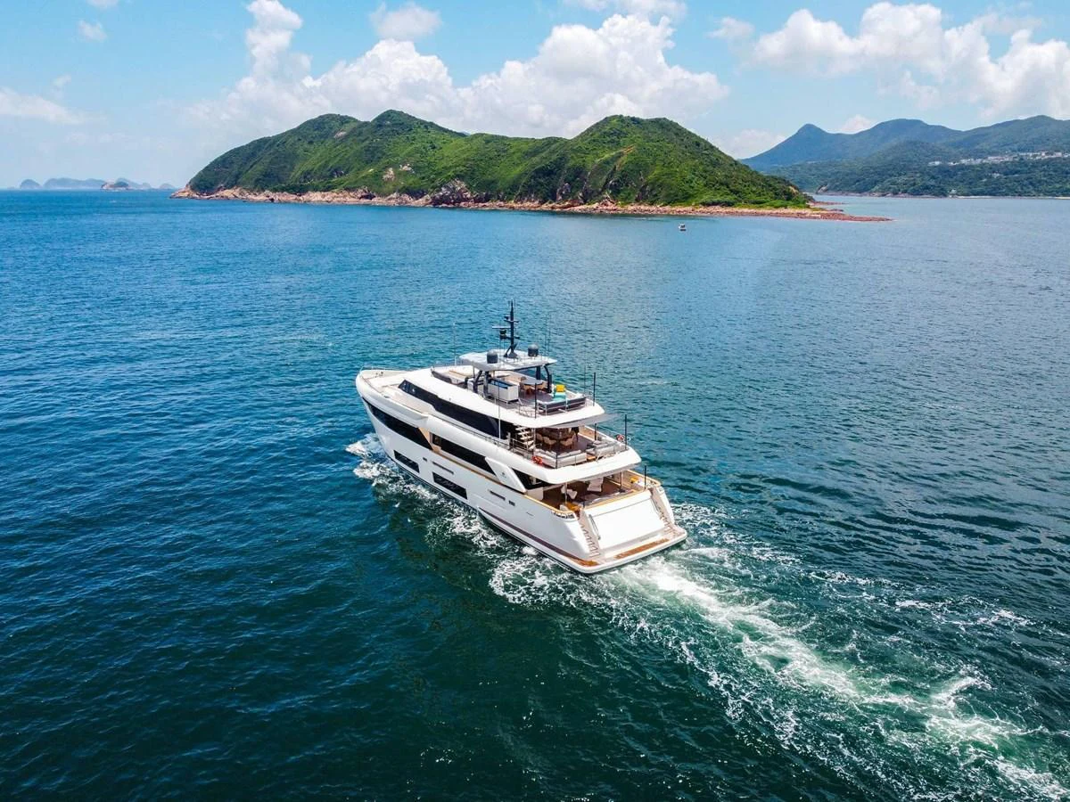 A luxurious yacht cruises through serene waters with a picturesque island backdrop. aboard CUSTOM LINE NAVETTA 33 Yacht for Sale