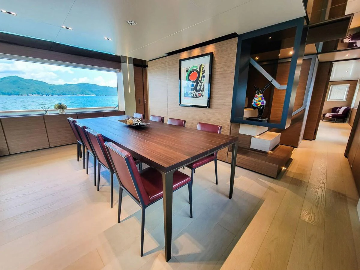 The yacht's dining area features a sleek table with red chairs, set against a backdrop of large windows offering stunning sea views. aboard CUSTOM LINE NAVETTA 33 Yacht for Sale
