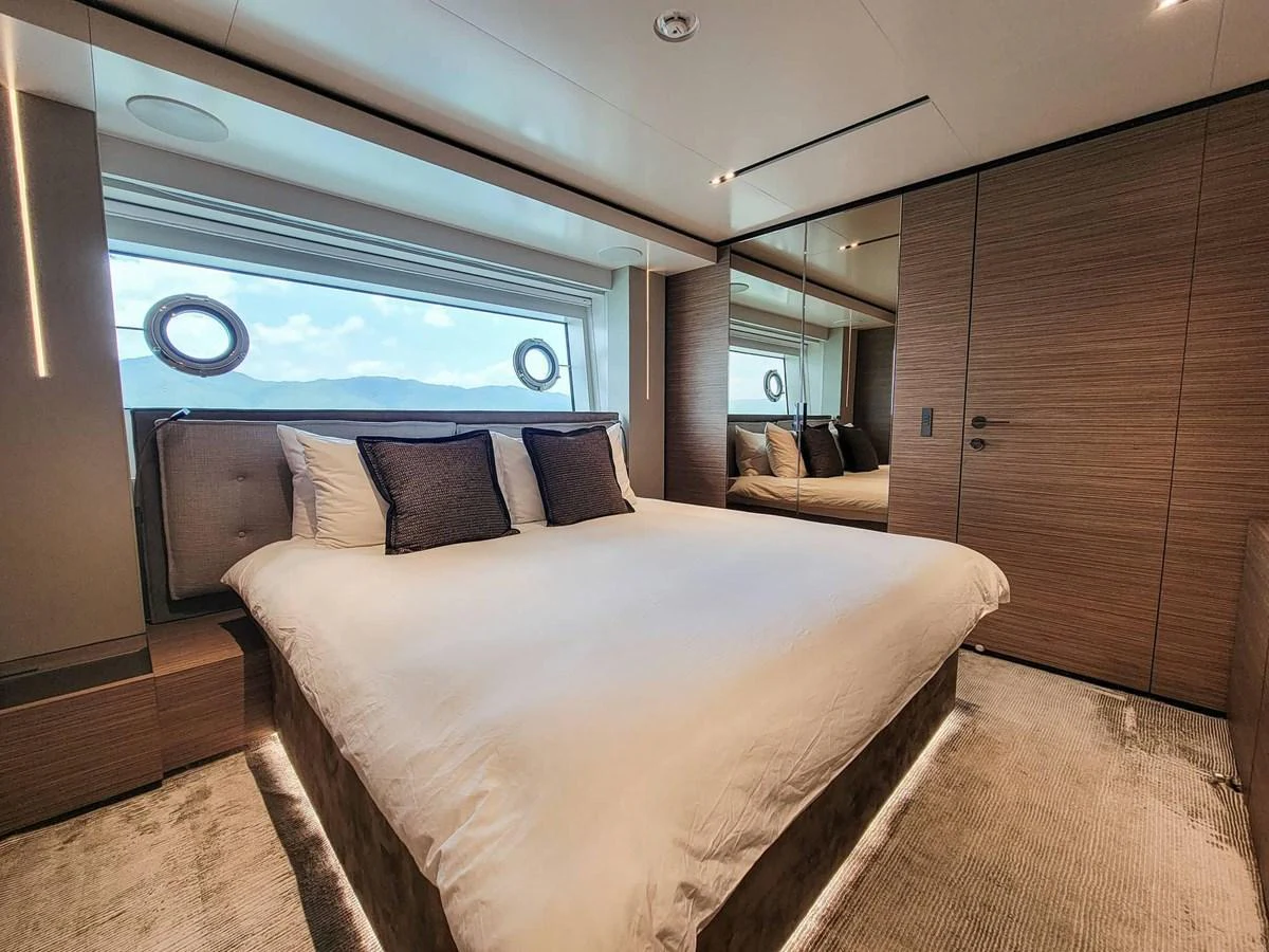 This elegant stateroom features a plush bed, modern wood paneling, and large windows offering stunning sea views. aboard CUSTOM LINE NAVETTA 33 Yacht for Sale