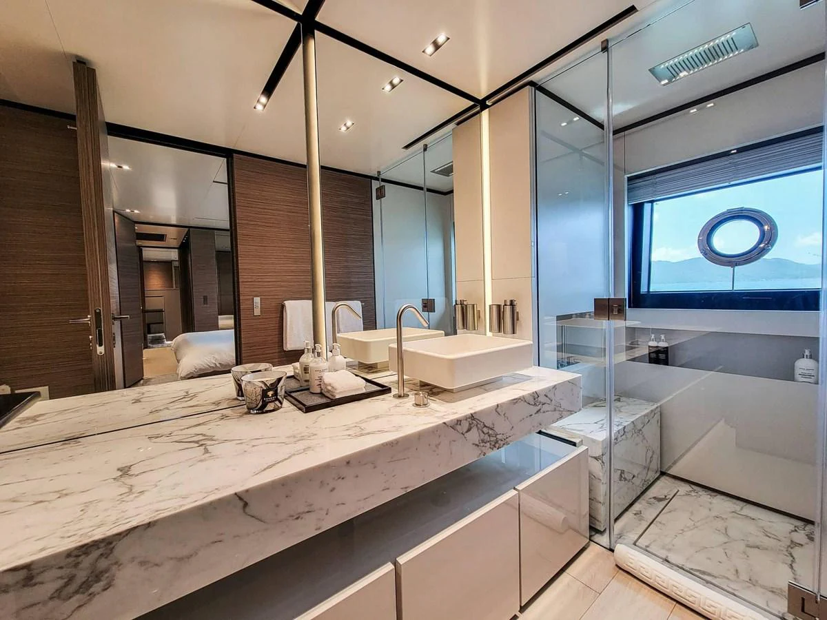 The yacht's bathroom features a luxurious marble countertop and a spacious glass-enclosed shower with a scenic window view. aboard CUSTOM LINE NAVETTA 33 Yacht for Sale