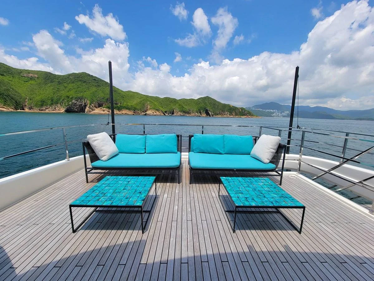 The sundeck features stylish turquoise seating with a stunning ocean and mountain backdrop. aboard CUSTOM LINE NAVETTA 33 Yacht for Sale