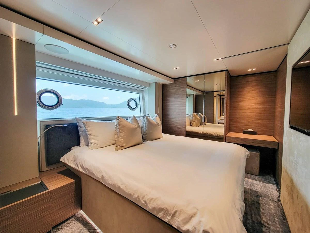 A luxurious stateroom featuring a large bed, modern decor, and a scenic ocean view through the window. aboard CUSTOM LINE NAVETTA 33 Yacht for Sale