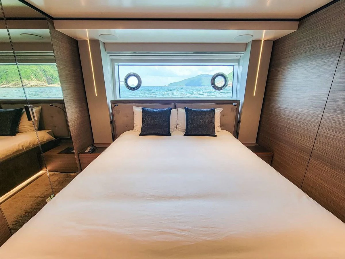 A luxurious stateroom with a large bed and scenic ocean view through the window. aboard CUSTOM LINE NAVETTA 33 Yacht for Sale