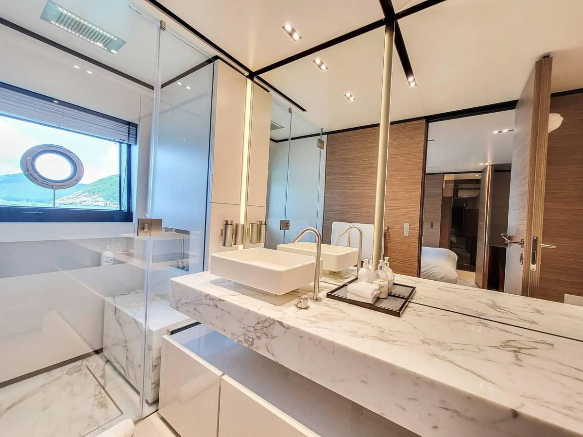 The yacht's bathroom features a luxurious marble countertop and modern fixtures, with a view of the sea through a porthole window. aboard CUSTOM LINE NAVETTA 33 Yacht for Sale