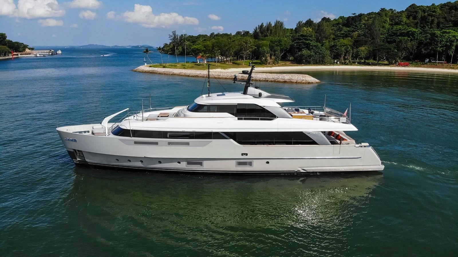 A sleek and modern yacht glides gracefully on calm waters near a lush, green shoreline. aboard SANLORENZO SD96 Yacht for Sale