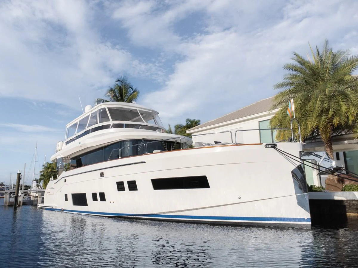 A sleek and modern yacht is docked in a serene marina, showcasing its elegant design and spacious upper deck. aboard FANTASEA Yacht for Sale