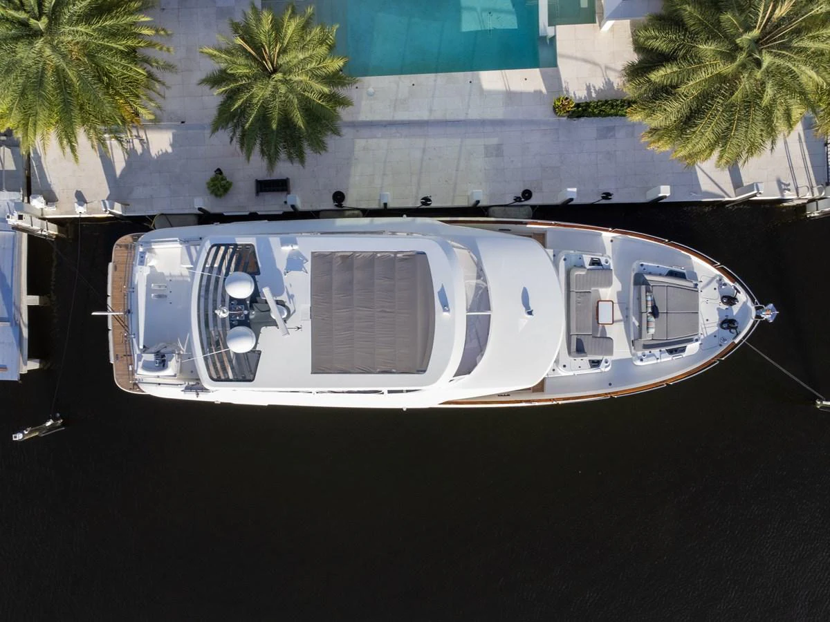 An aerial view of a sleek yacht docked at a marina, surrounded by palm trees and a pool. aboard FANTASEA Yacht for Sale