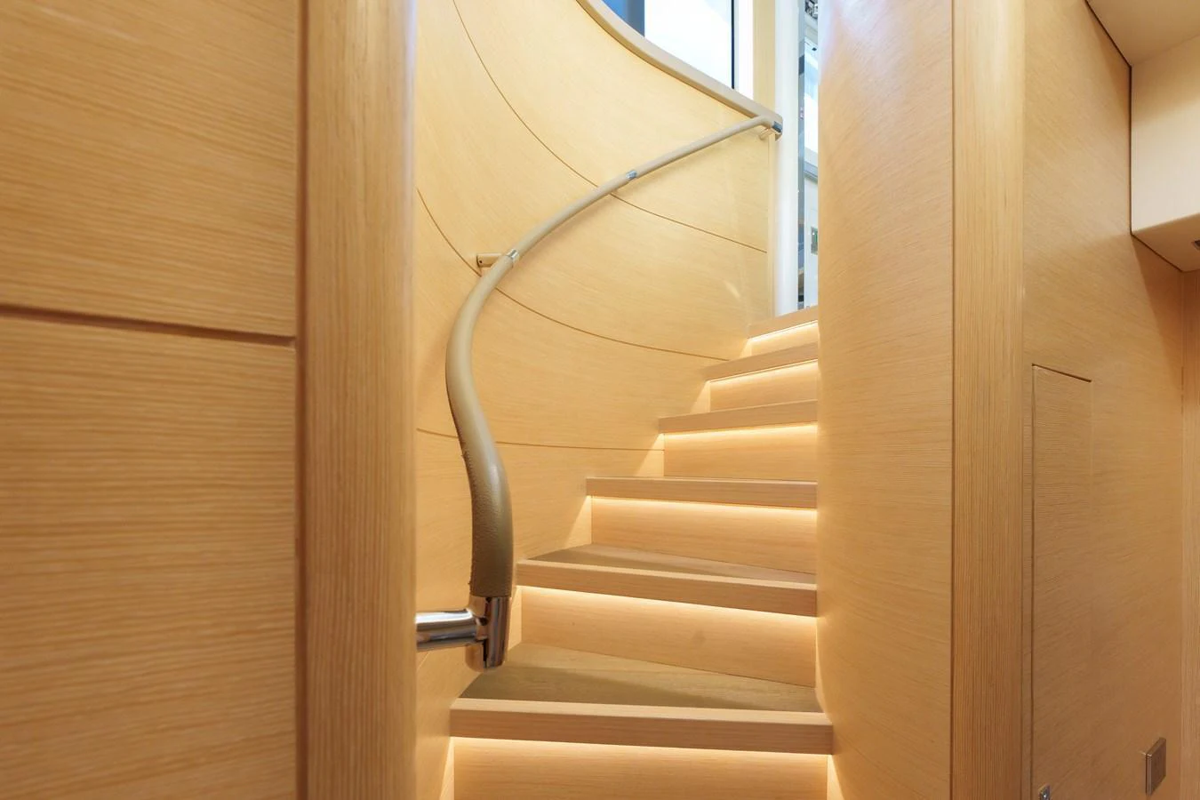 A beautifully designed interior staircase with warm lighting and sleek wooden finishes. aboard FANTASEA Yacht for Sale