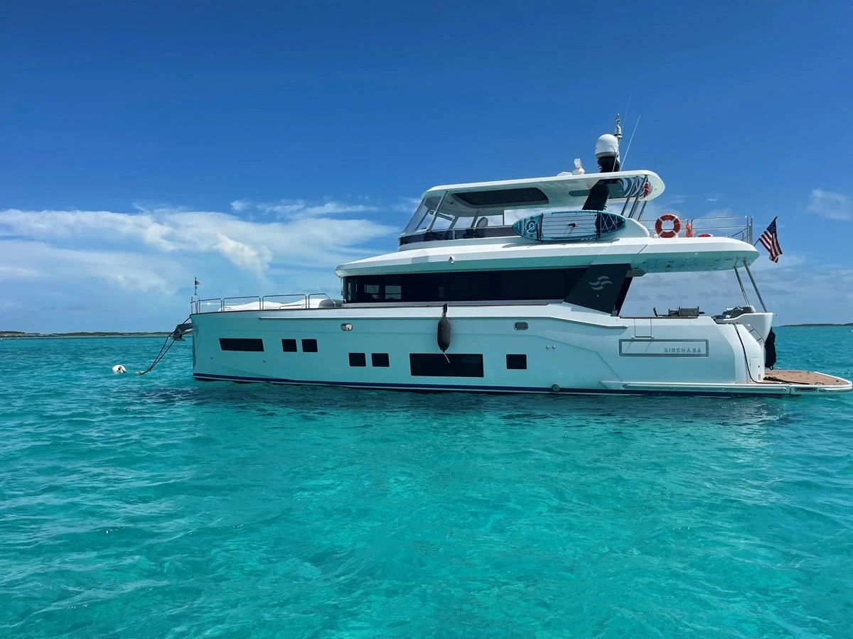 A sleek and modern yacht is anchored in crystal-clear turquoise waters under a bright blue sky. aboard FANTASEA Yacht for Sale