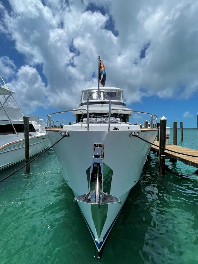 A stunning yacht is docked at a marina, showcasing its sleek bow and polished exterior under a bright blue sky. aboard FANTASEA Yacht for Sale