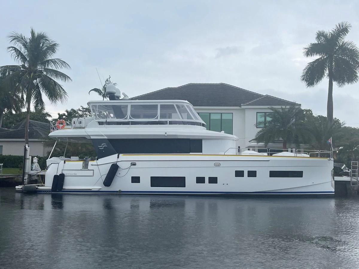 A sleek and modern yacht is docked in a serene waterfront setting, showcasing its elegant profile and spacious upper deck. aboard FANTASEA Yacht for Sale