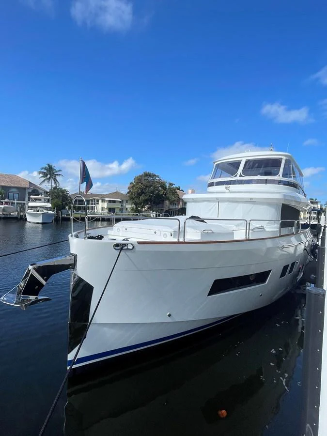 A sleek and modern yacht is docked in a serene marina under a clear blue sky. aboard FANTASEA Yacht for Sale