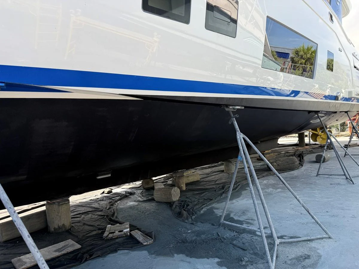 The yacht is seen on dry dock, supported by stands, showcasing its hull and part of the superstructure. aboard FANTASEA Yacht for Sale