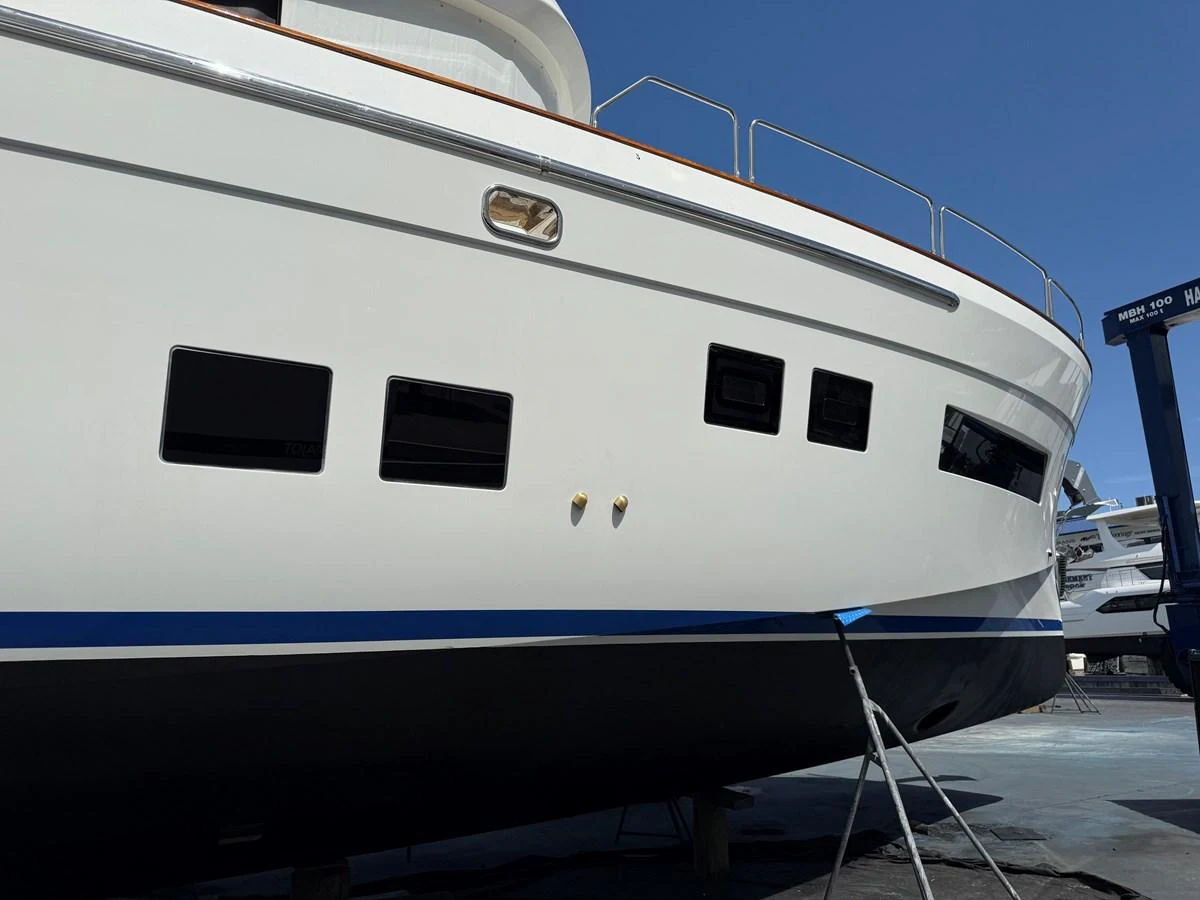 The yacht's sleek exterior showcases a pristine white hull with modern windows and a blue accent stripe. aboard FANTASEA Yacht for Sale