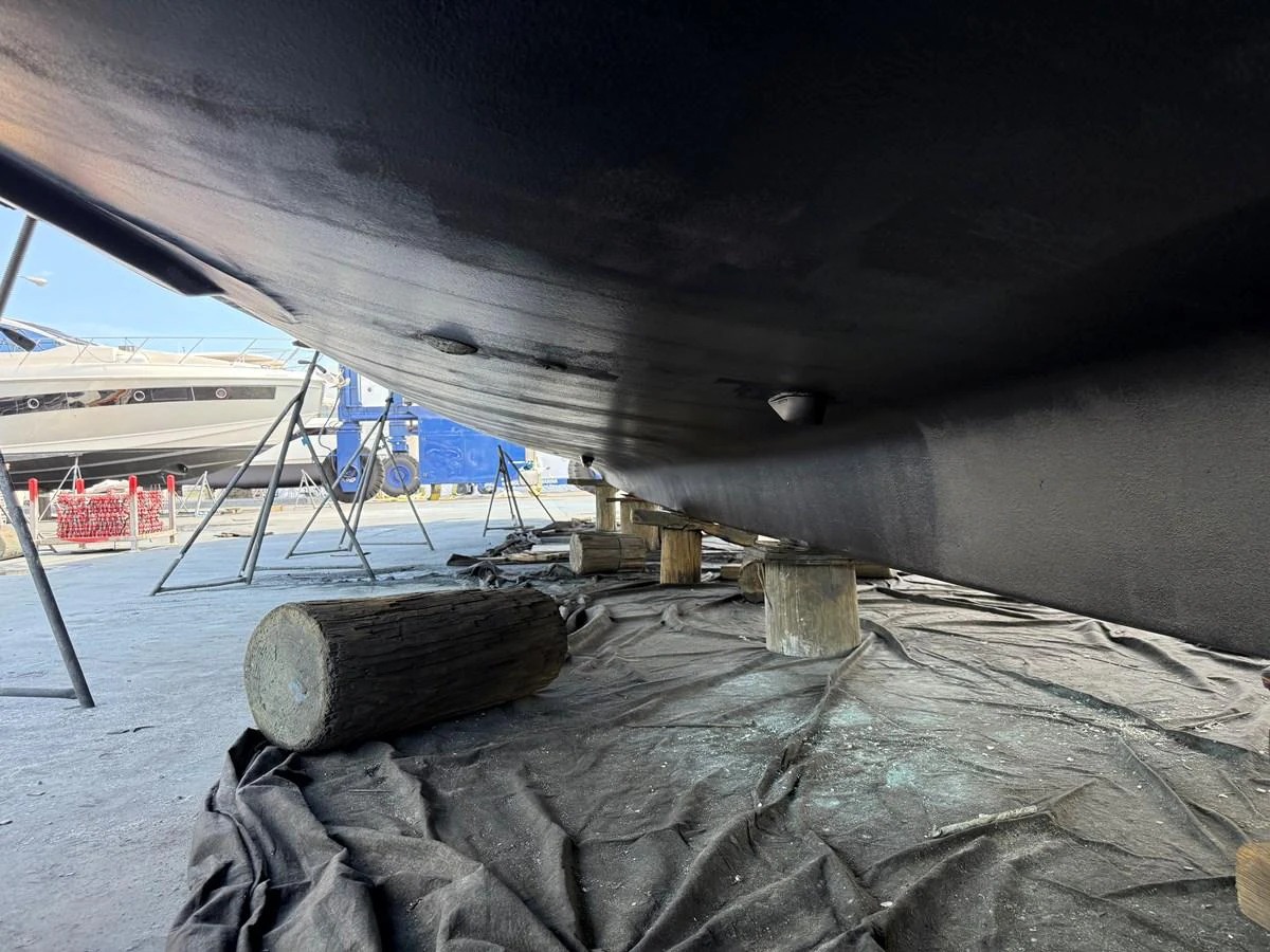 The image shows the underside of a yacht, supported by wooden blocks during maintenance. aboard FANTASEA Yacht for Sale