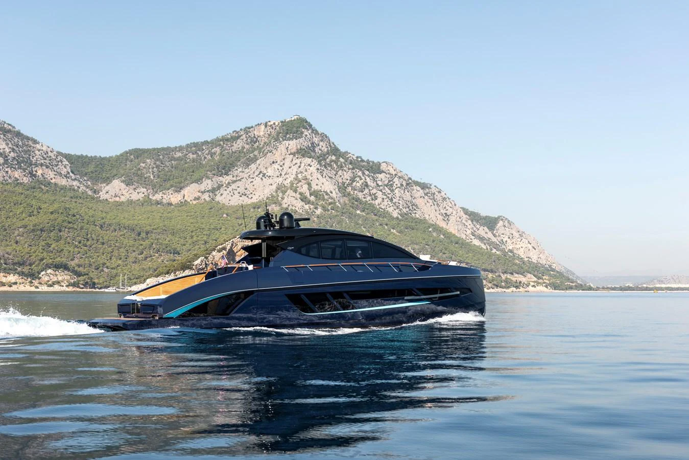 A sleek and modern yacht cruises along a serene coastline with mountainous scenery. aboard NEW BUILD Yacht for Sale