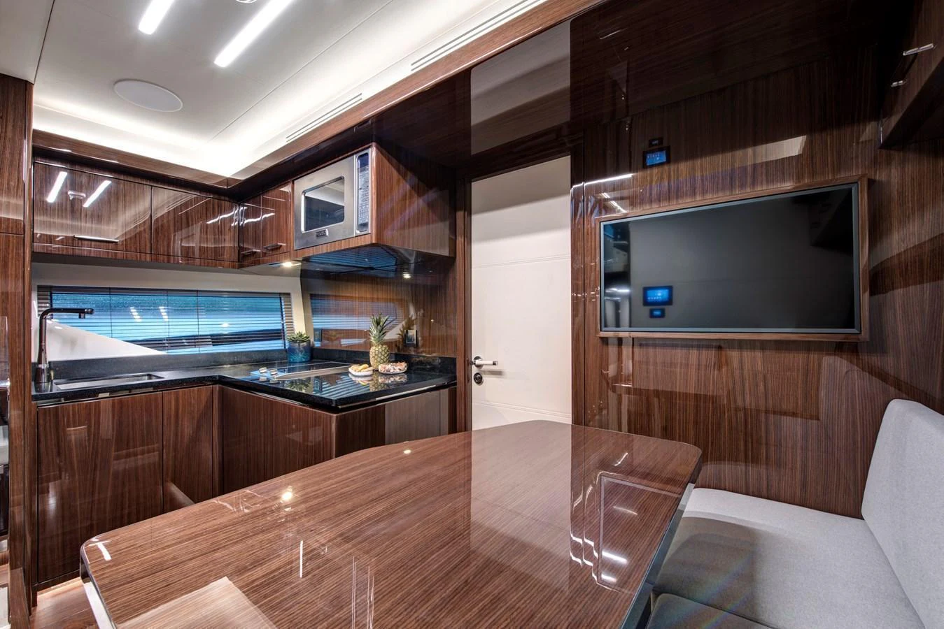 The yacht's galley features sleek wood finishes, modern appliances, and a comfortable dining area. aboard NEW BUILD Yacht for Sale
