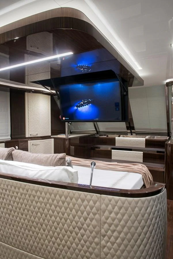 The stateroom features a luxurious bed with quilted headboard and a retractable TV for ultimate relaxation. aboard NEW BUILD Yacht for Sale