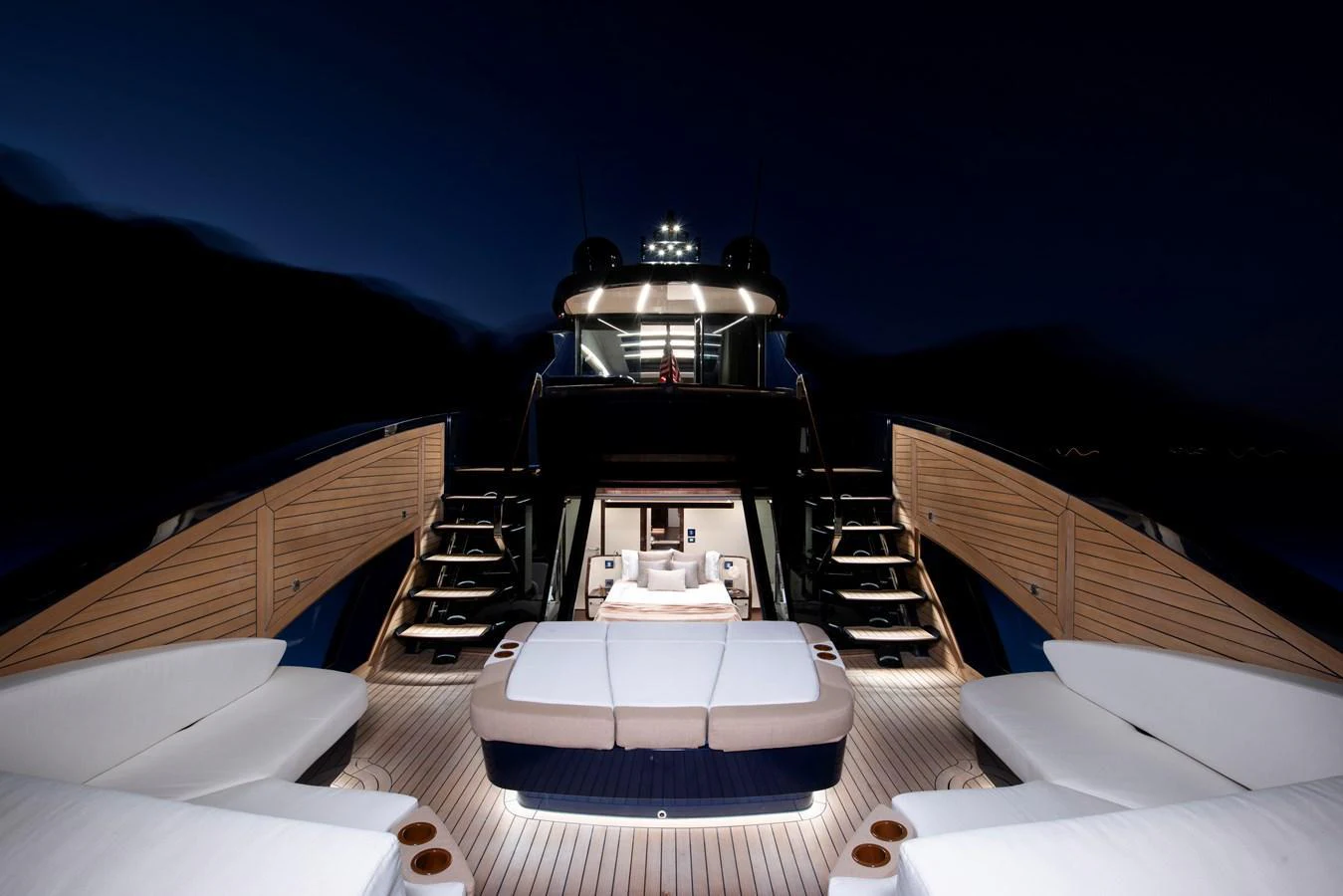 The aft deck of the yacht is beautifully illuminated at night, featuring luxurious seating and a central sunbed. aboard NEW BUILD Yacht for Sale