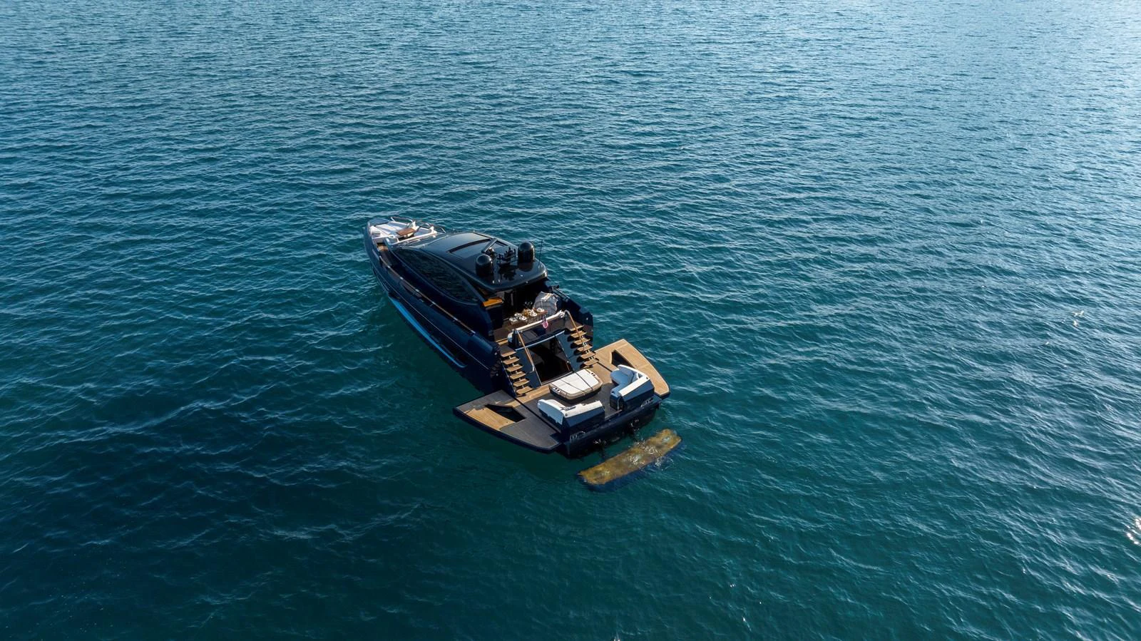 A sleek yacht is anchored in calm, blue waters, showcasing its modern design and spacious deck. aboard NEW BUILD Yacht for Sale