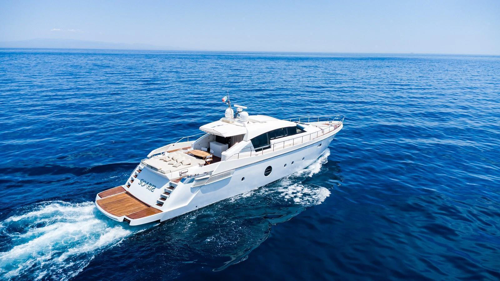 A sleek yacht glides through the open sea under a clear blue sky. aboard LUCHI Yacht for Sale