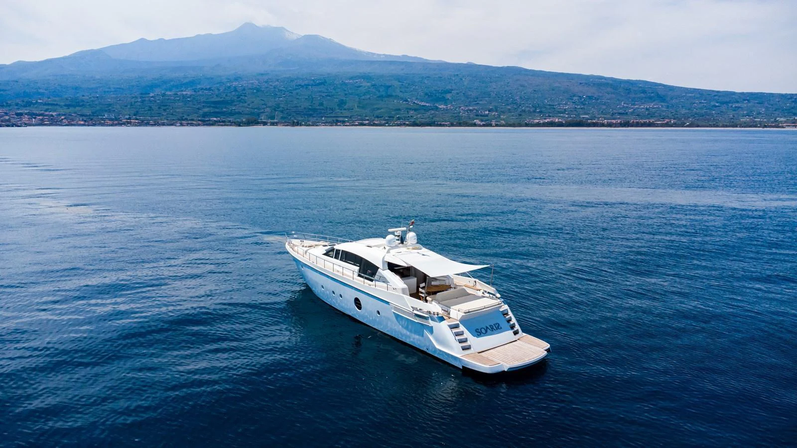 A sleek yacht cruises gracefully on calm waters with a mountainous backdrop. aboard LUCHI Yacht for Sale