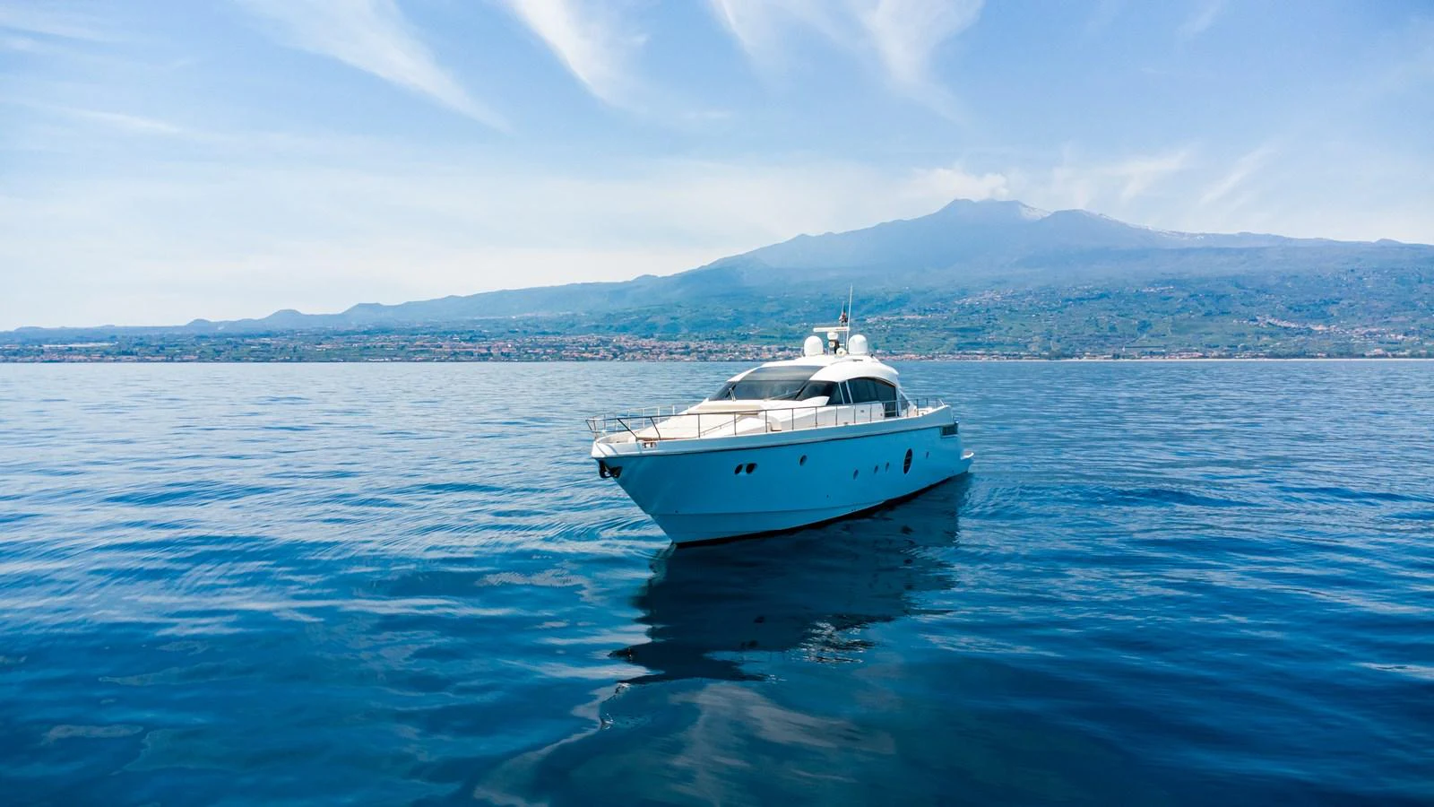 A sleek yacht glides gracefully on calm waters with a scenic mountain backdrop. aboard LUCHI Yacht for Sale
