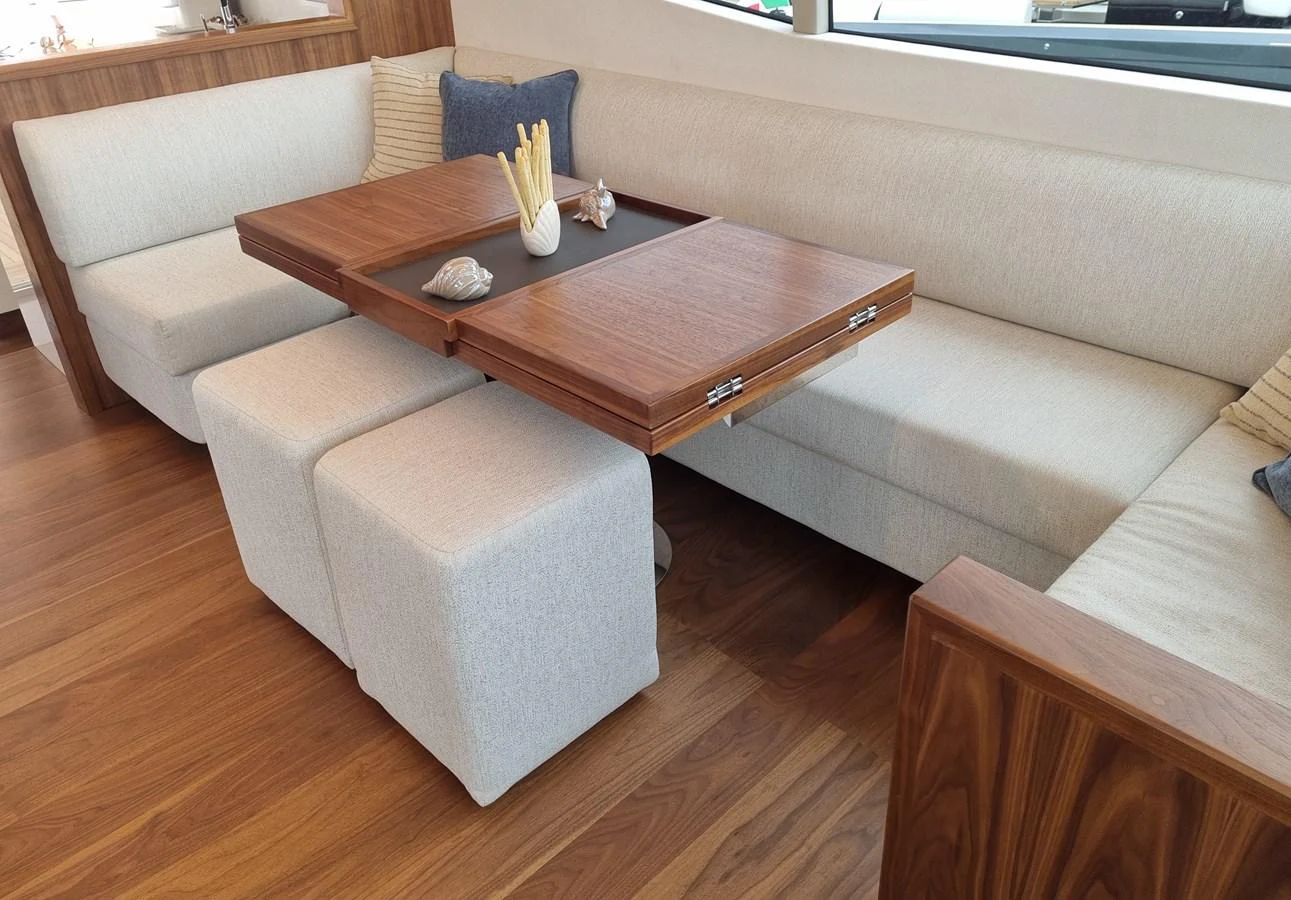 The salon features a cozy seating area with a versatile wooden table and plush cushions. aboard MONACHUS 70 FLY Yacht for Sale