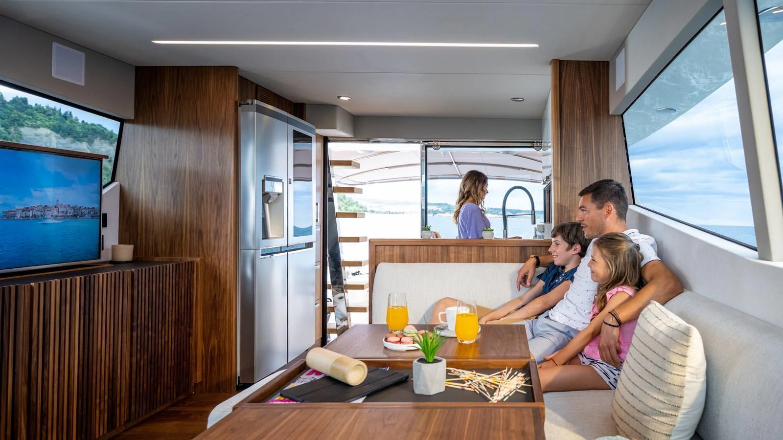 A cozy salon with a family enjoying a movie and refreshments. aboard MONACHUS 70 FLY Yacht for Sale