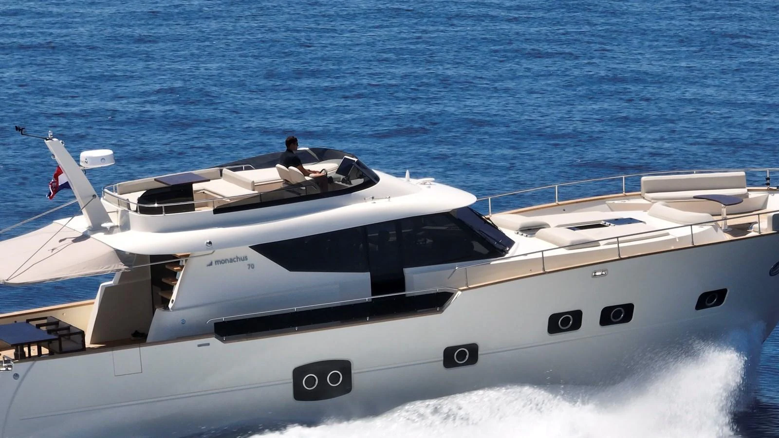 A sleek yacht cruises through the water, showcasing its modern design and spacious upper deck. aboard MONACHUS 70 FLY Yacht for Sale