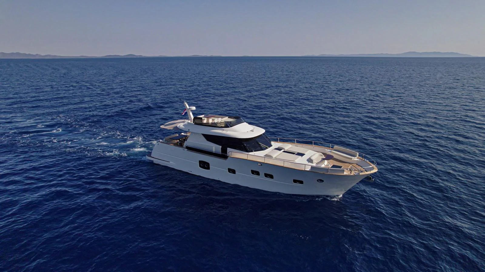 A sleek yacht cruises through calm blue waters under a clear sky. aboard MONACHUS 70 FLY Yacht for Sale