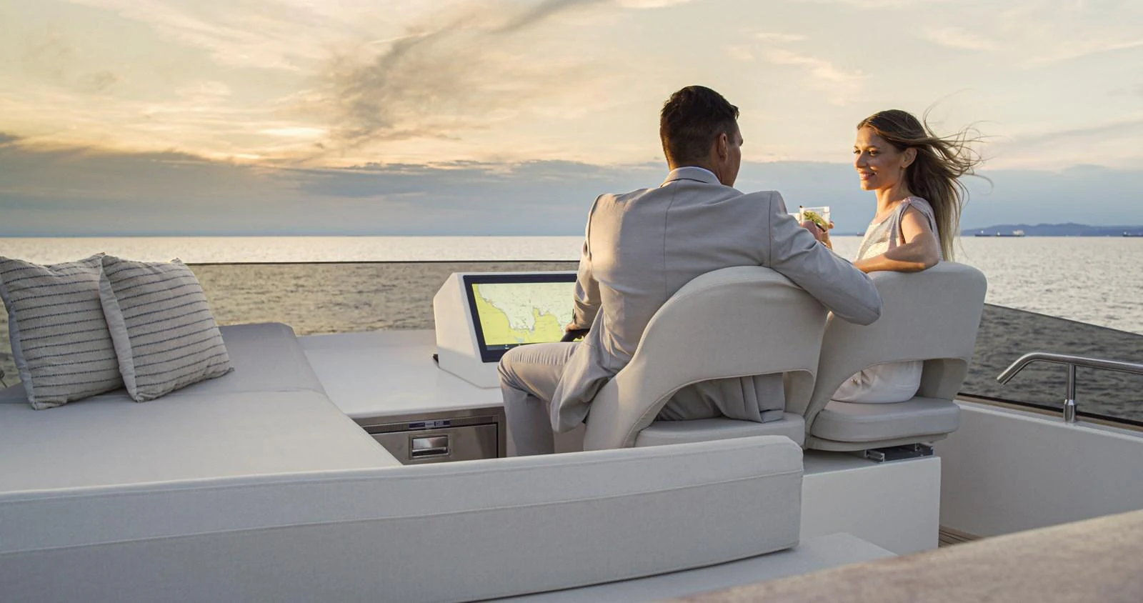A couple enjoys a serene evening on the aft deck of a luxurious yacht, with a stunning ocean view. aboard MONACHUS 70 FLY Yacht for Sale