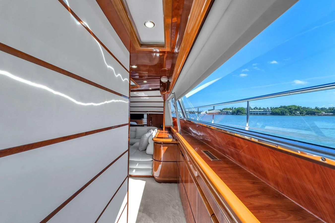 The yacht's interior features a sleek hallway with polished wood finishes and large windows offering a scenic view. aboard FERRETTI YACHTS CUSTOM LINE 94 Yacht for Sale