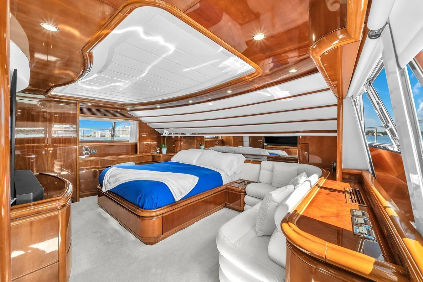 The master stateroom features luxurious wood finishes, a plush bed with blue accents, and ample natural light. aboard FERRETTI YACHTS CUSTOM LINE 94 Yacht for Sale