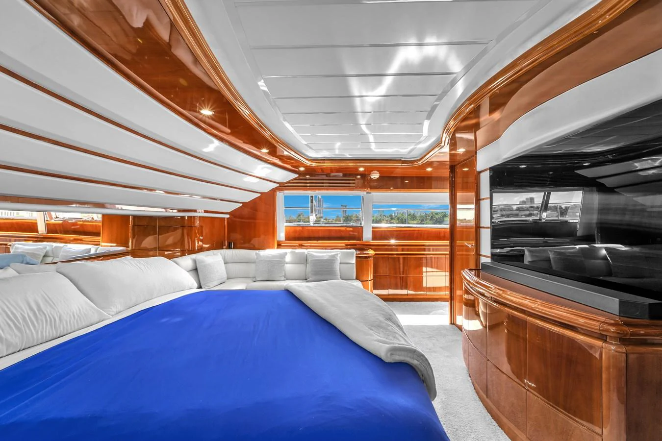 The master stateroom features luxurious wood paneling, a large bed with a blue cover, and expansive windows offering stunning views. aboard FERRETTI YACHTS CUSTOM LINE 94 Yacht for Sale