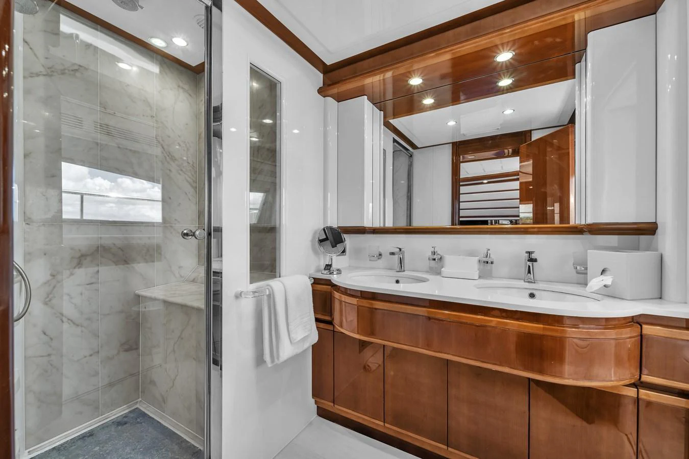 The yacht's bathroom features elegant wood cabinetry and a spacious shower with marble accents. aboard FERRETTI YACHTS CUSTOM LINE 94 Yacht for Sale