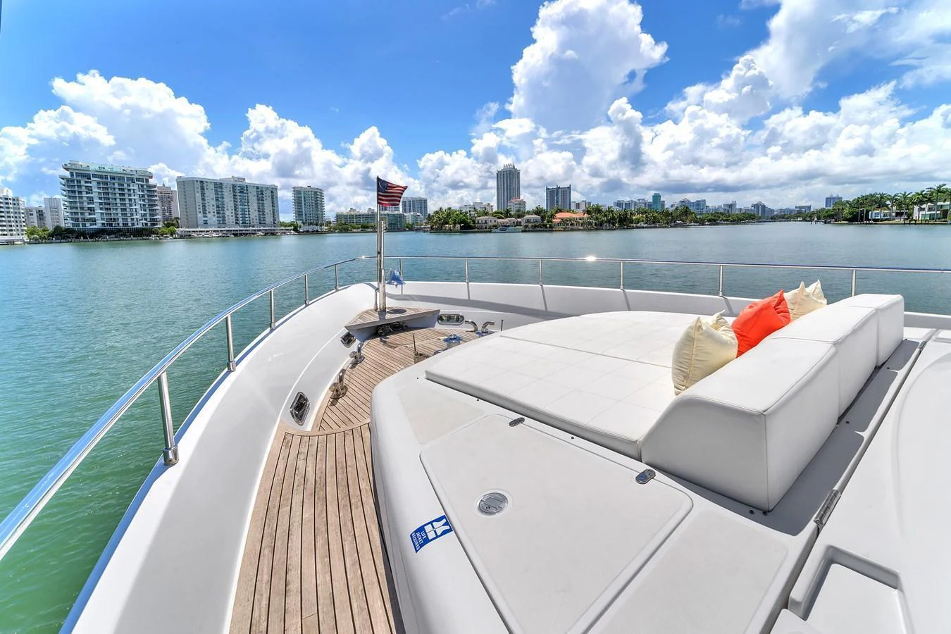 The yacht's foredeck features a spacious sunbathing area with plush cushions, offering stunning views of the city skyline. aboard FERRETTI YACHTS CUSTOM LINE 94 Yacht for Sale