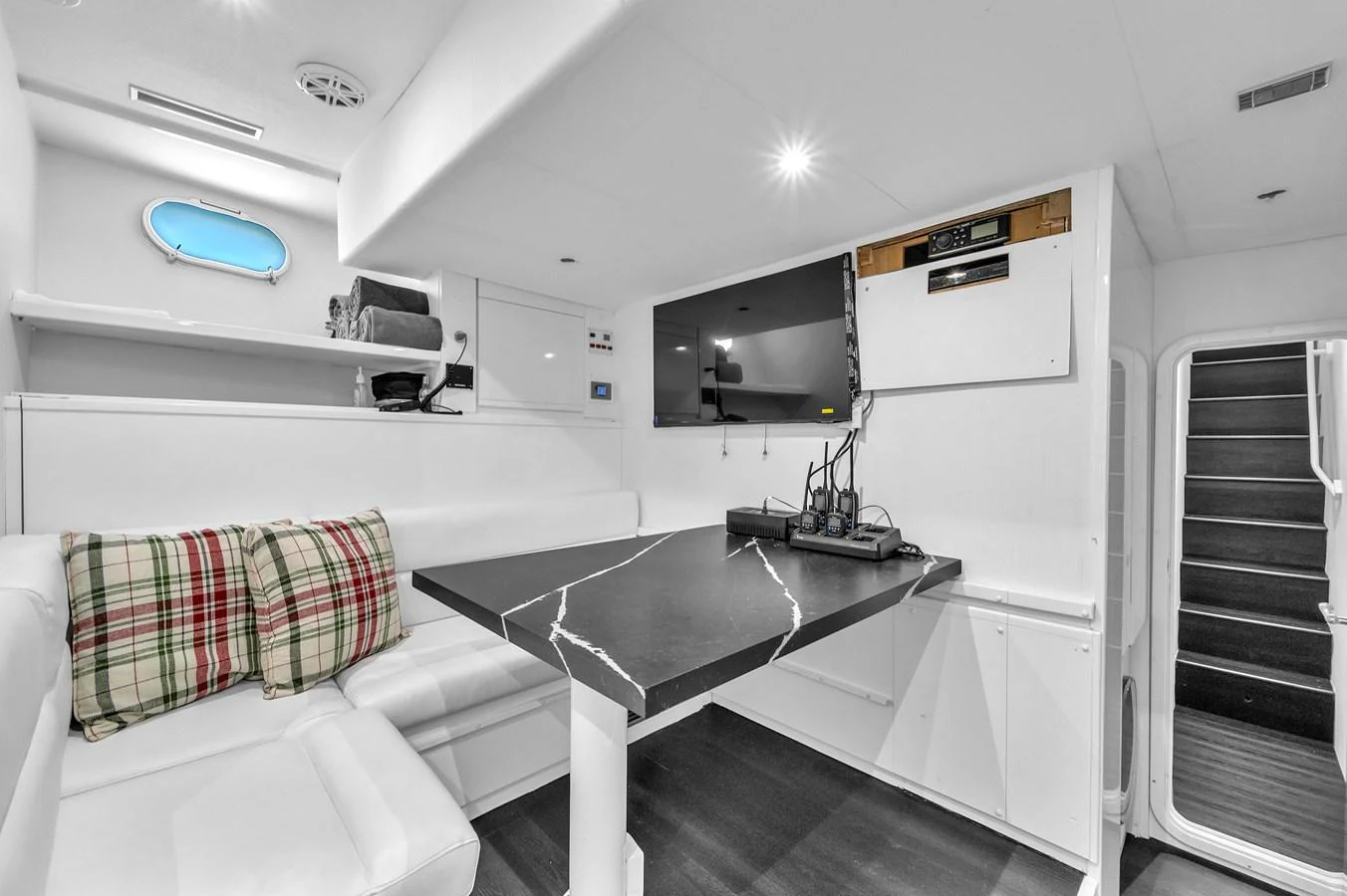 This cozy interior space features a sleek black table, white seating, and modern amenities. aboard FERRETTI YACHTS CUSTOM LINE 94 Yacht for Sale