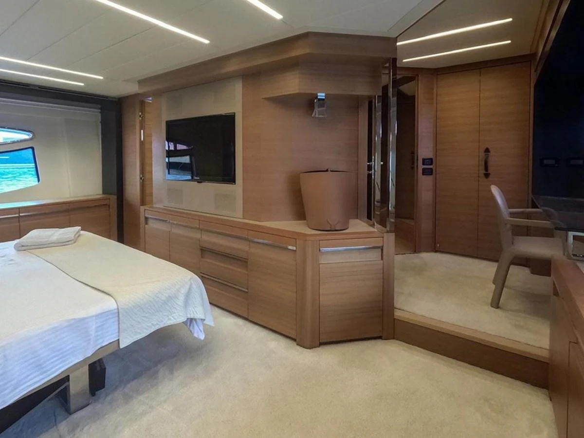 The stateroom features elegant wood finishes, a plush bed, and modern amenities for a luxurious stay. aboard HONEY BADGER Yacht for Sale