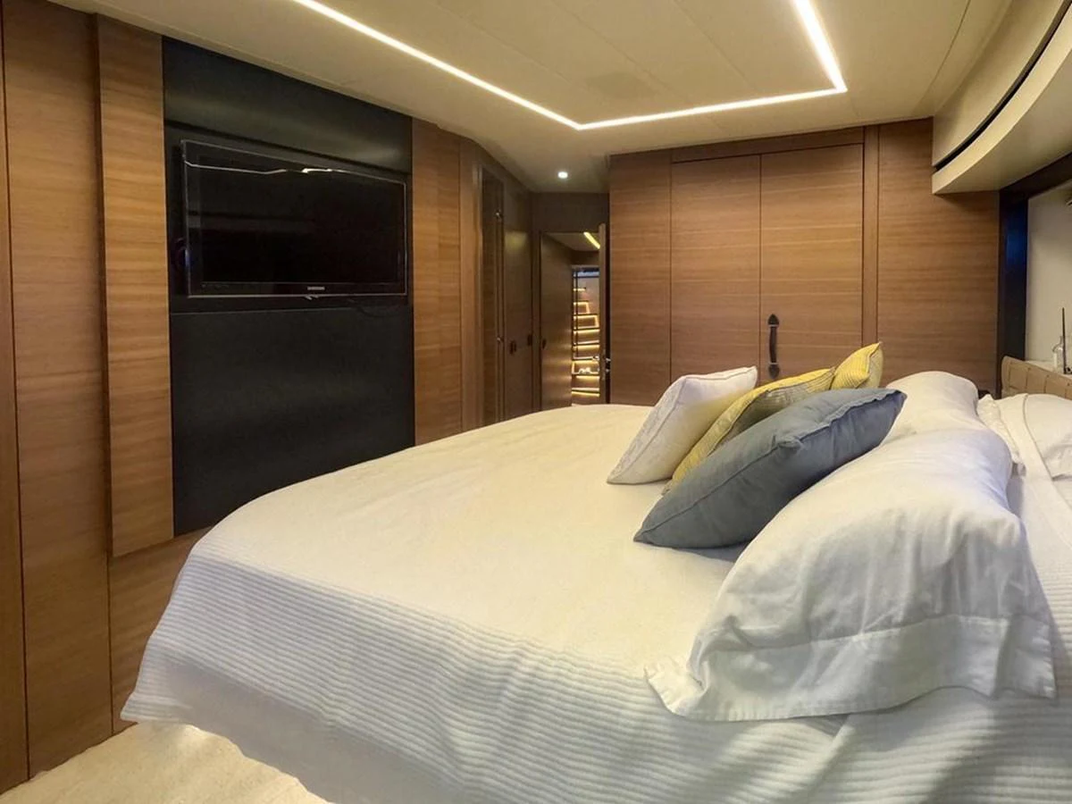 A luxurious stateroom featuring a large bed with plush pillows and modern wood paneling. aboard HONEY BADGER Yacht for Sale