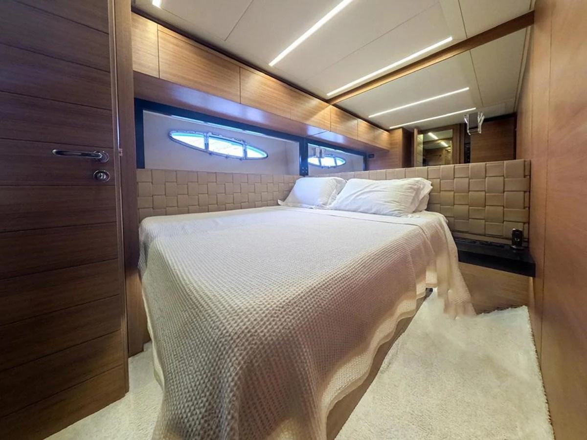 The stateroom features a cozy bed with elegant wood paneling and soft lighting. aboard HONEY BADGER Yacht for Sale