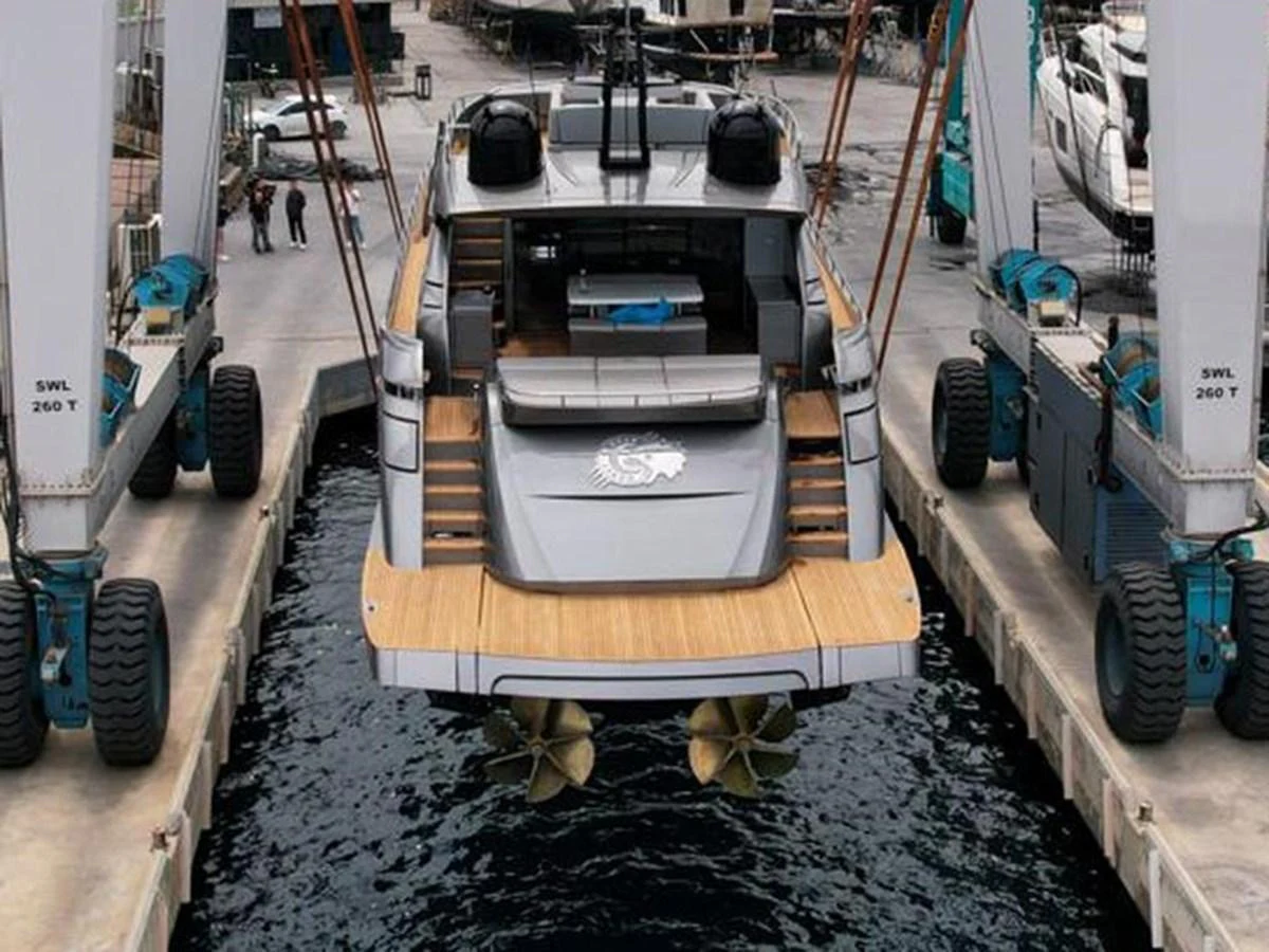 The yacht is being lifted out of the water by a large crane in a shipyard. aboard HONEY BADGER Yacht for Sale